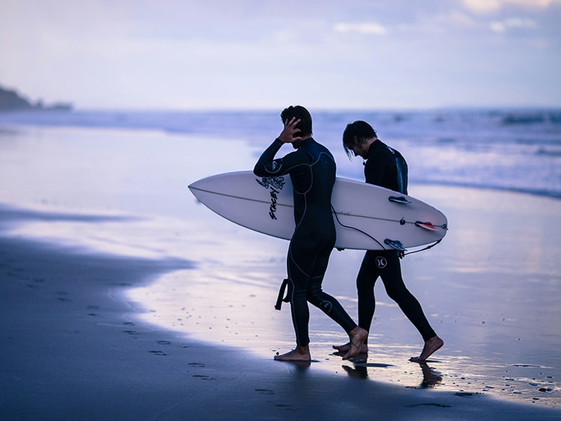 Two surfers in wet-suits coming out of the water at Bells Beach, Victoria, Australia