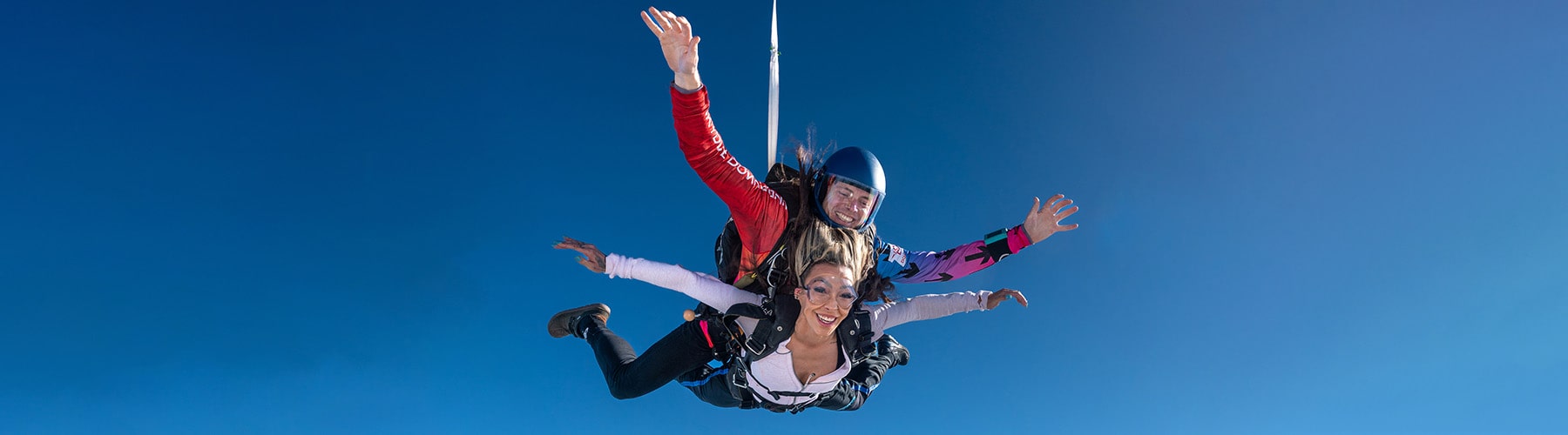 A happy woman in freefall skydiving with her tandem master