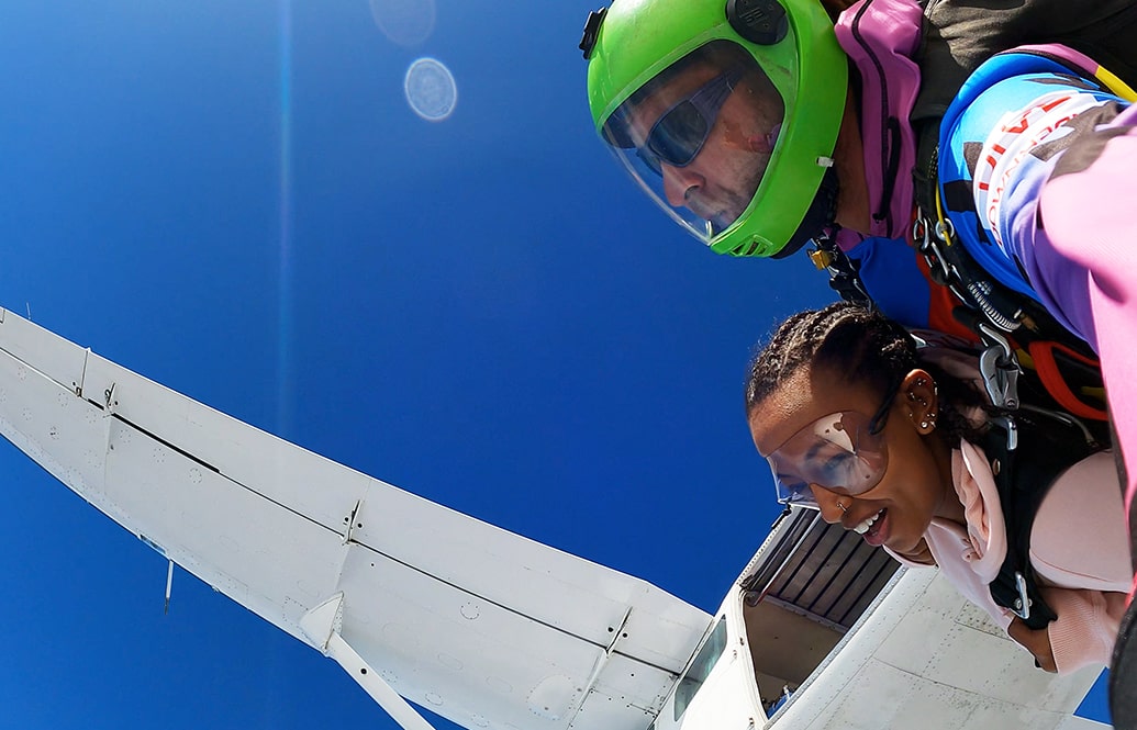 A tandem skydiver exiting the plan after her friends.