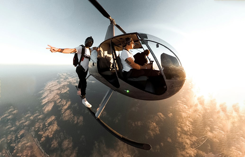 Professional skydiver preparing to jump out of a helicopter. Doing a peace sign to the camera.