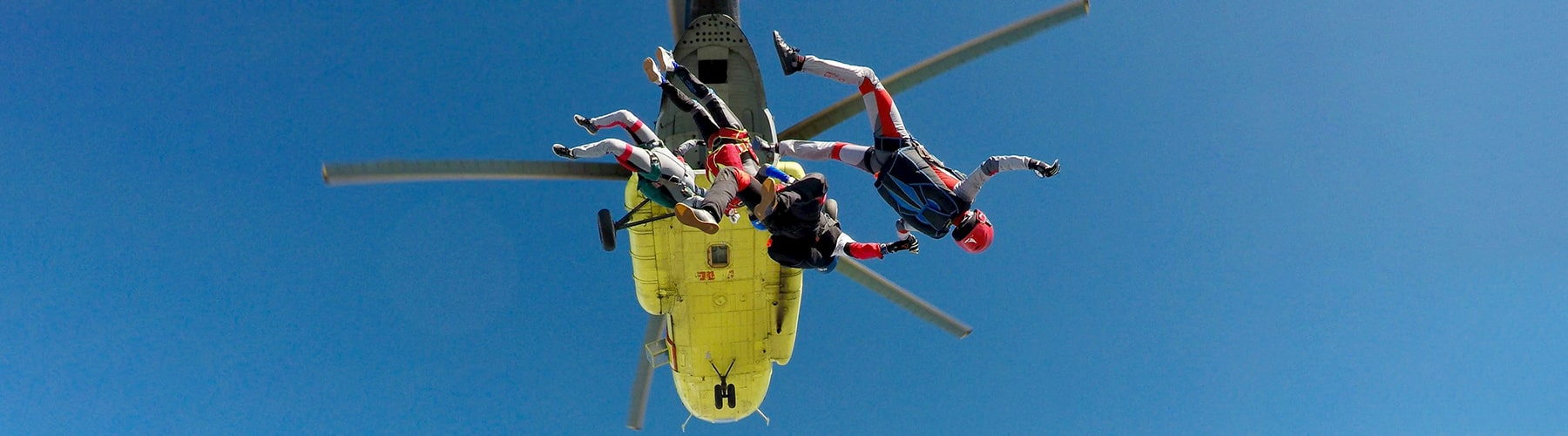 Three skydivers jumping out of a helicopter.